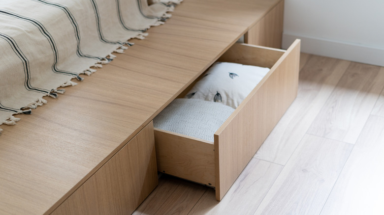 Hidden storage compartment beneath bed in the bedframe