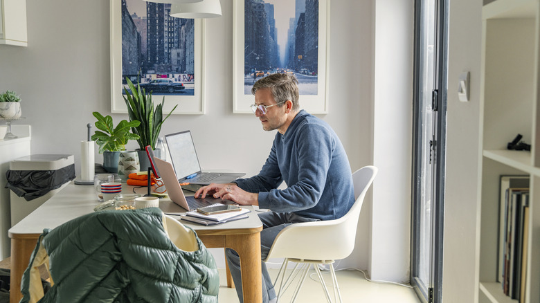 A man working at a home office desk with dustbin in the front