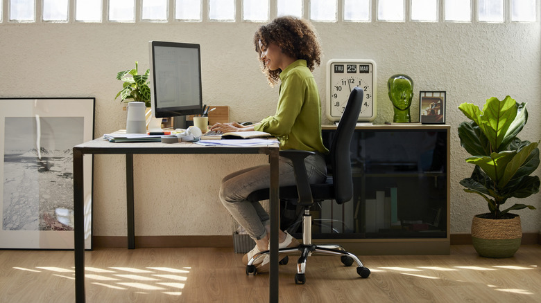 A woman sitting in a chair with the wrong height desk