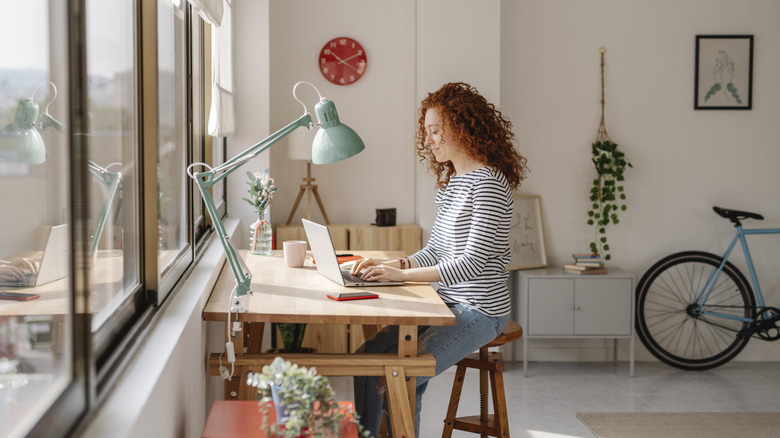 Woman sitting at a desk facing windows in a home office