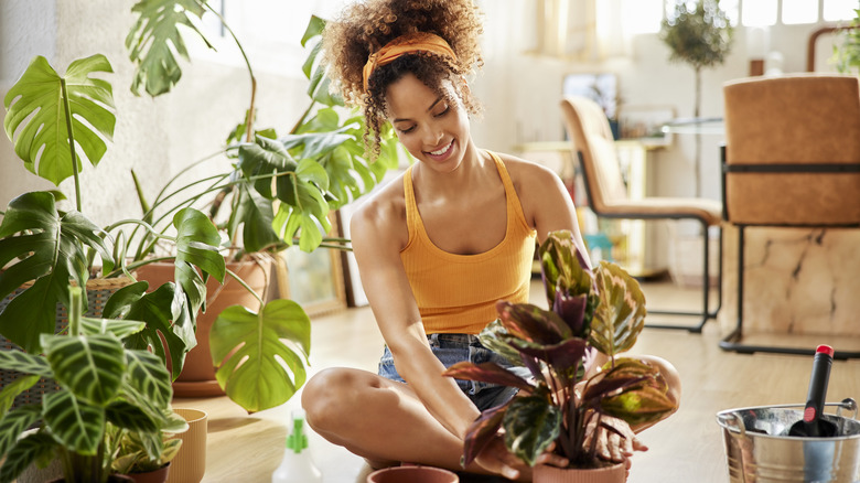 Woman sitting on floor while caring for a houseplant