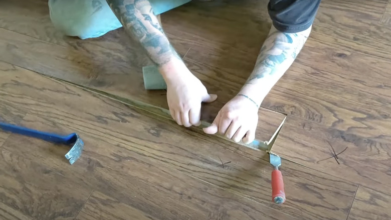 person pulling up a wood plank with their hands