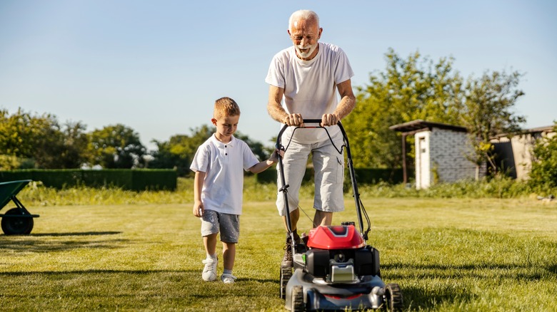 child mowing with adult