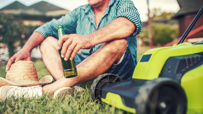 holding beer by lawn mower