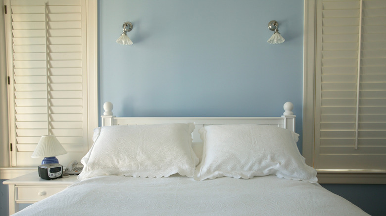 Light blue wall behind a white bed