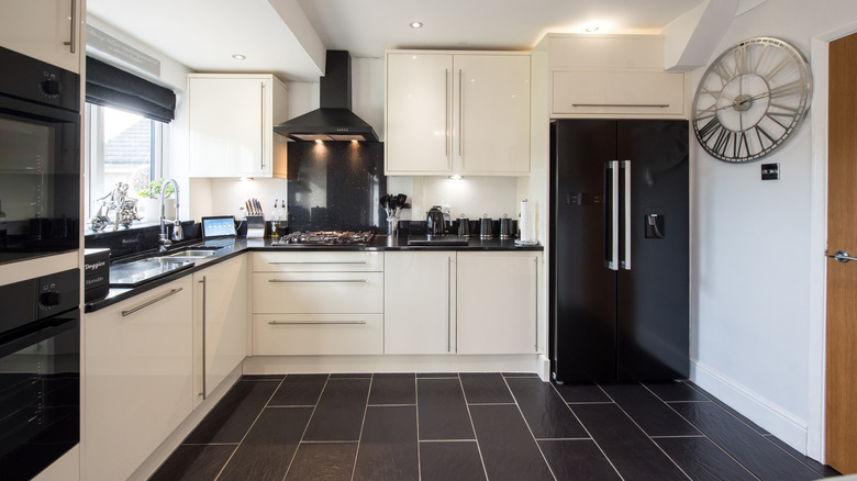 A kitchen with a black tile floor and white cabinets