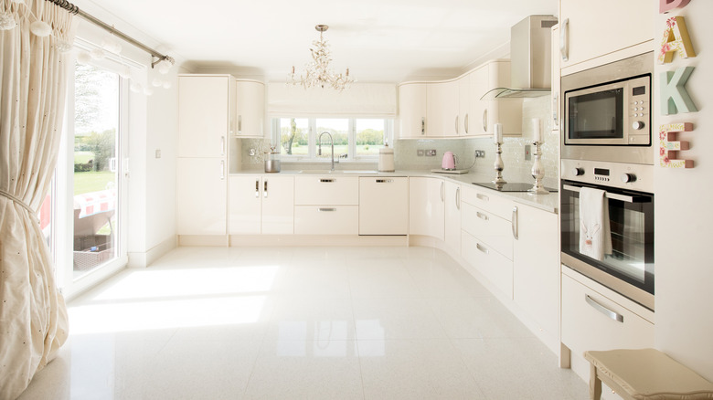 A kitchen with a glossy white tile floor reflecting lots of glare from a sliding door