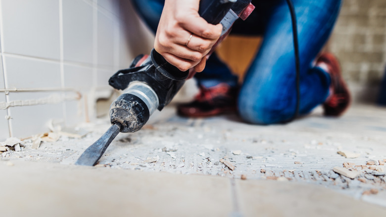 A person taking out old tile flooring