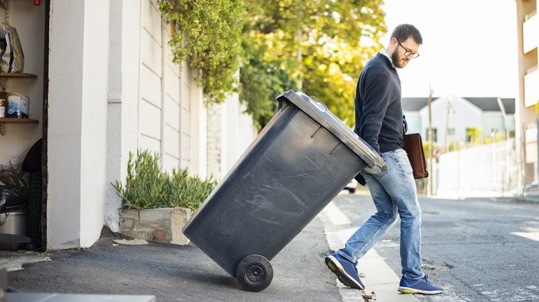 Man pulling trash can from garage