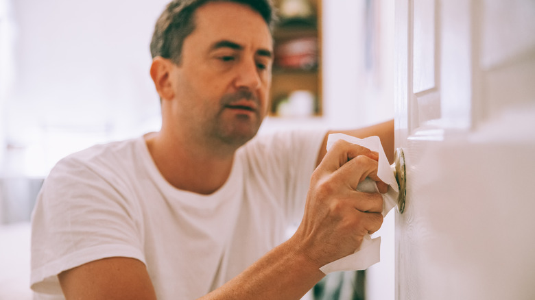 Man sanitizing door knob