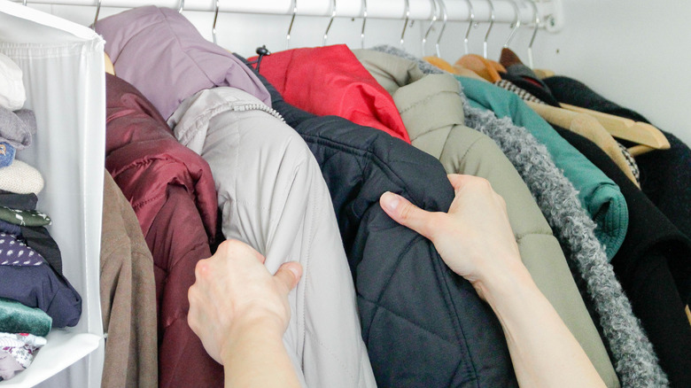 Hands touching winter coats on hangers