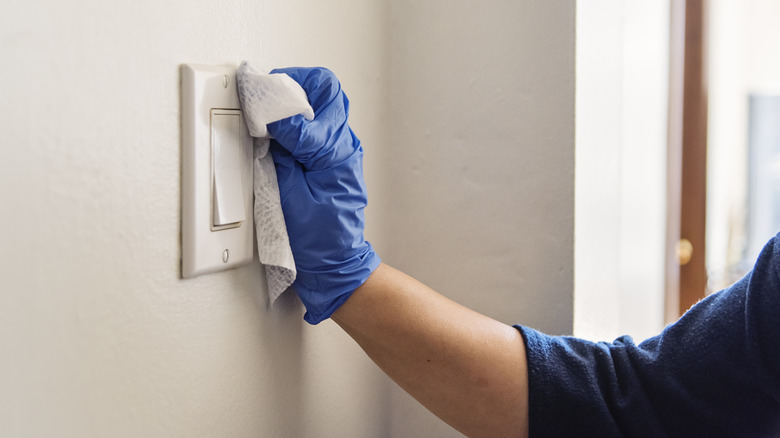 person cleaning light switch