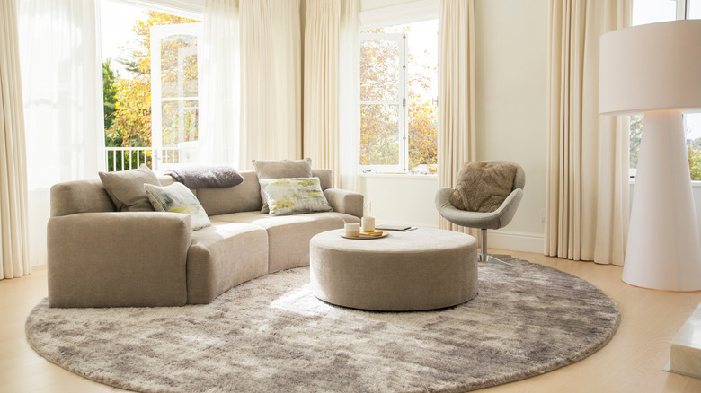 Gray curved sofa with ottoman and chair in living room