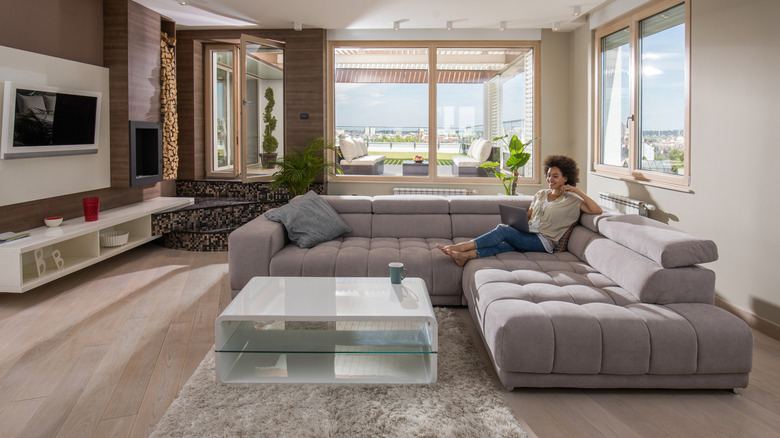 Woman sitting on a low-back sofa with a laptop