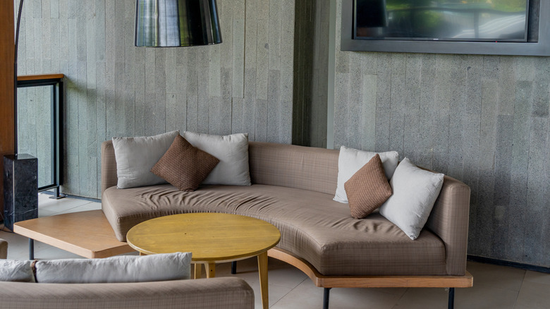 A brown semi-circular sofa around wood table in living room