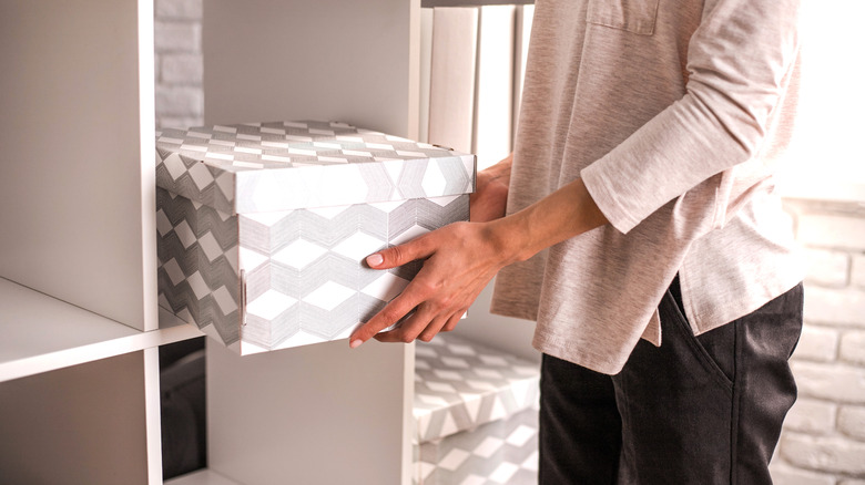 person putting box on shelf