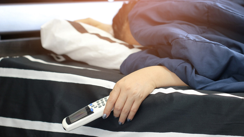 Person sleeping while holding temperature control remote