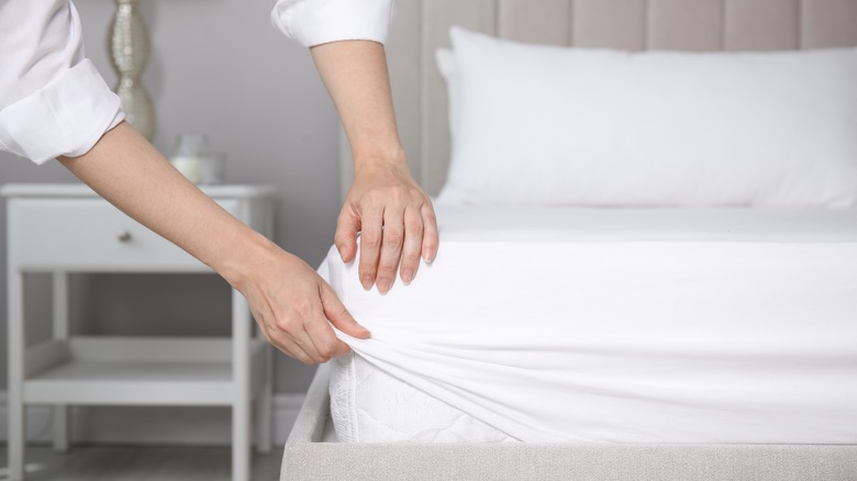 woman putting on fitted sheet