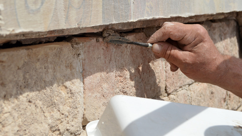 Person applying epoxy resin to gaps in stone wall