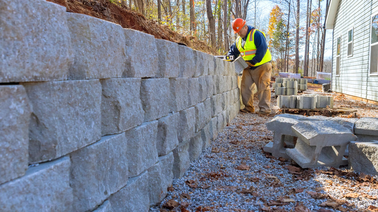 Contractor creating a retaining wall out of cinder blocks