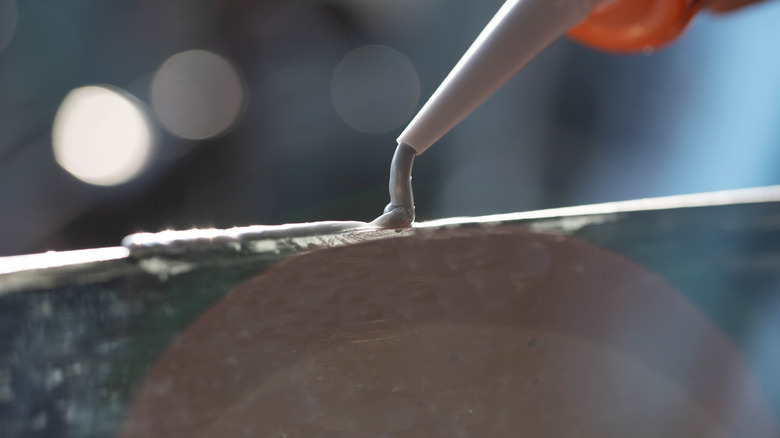 Applying silicone adhesive to a tile