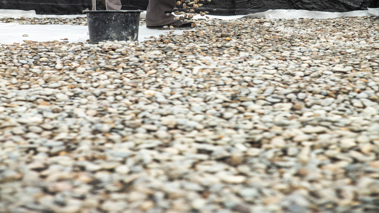 Man pouring gravel over white tarp