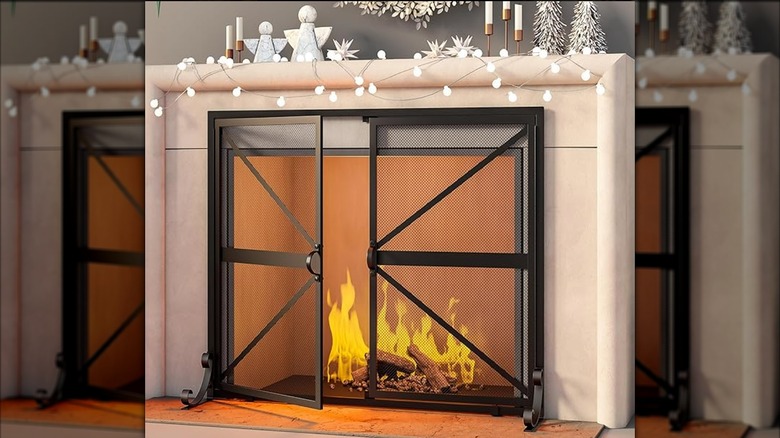 Black fireplace screen with two doors covering a decorative fireplace