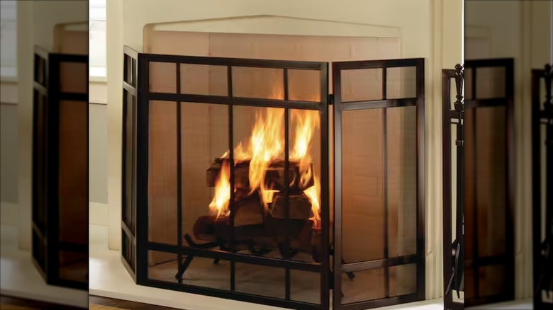 Black three-panel fireplace screen in front of a living room fireplace