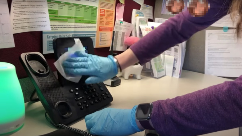 Person wiping down office phone