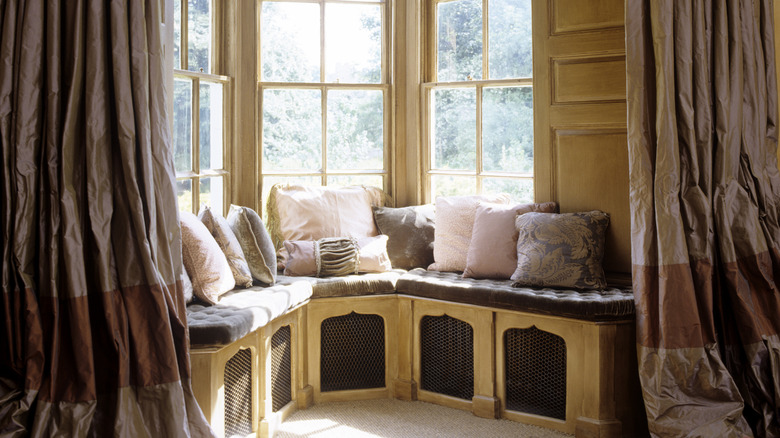 A bay window with window seating framed by curtains