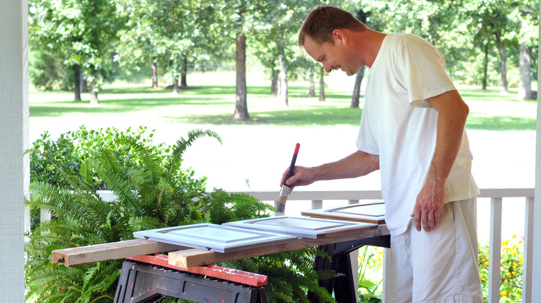 A person is painting uninstalled cabinet doors outside