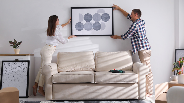 Couple hanging art on wall