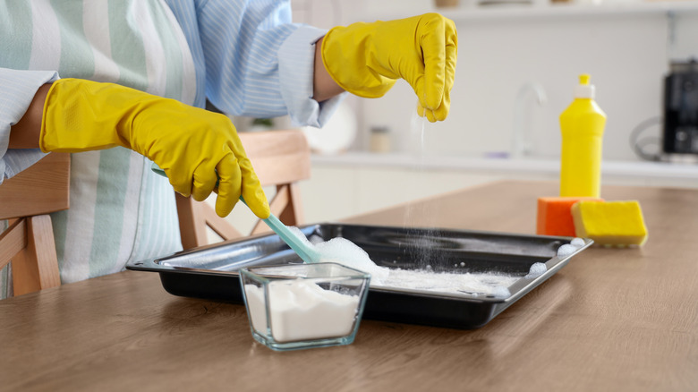 person cleaning baking tray with baking soda