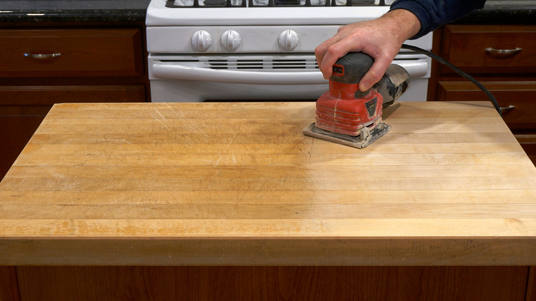 Person sanding a wooden countertop