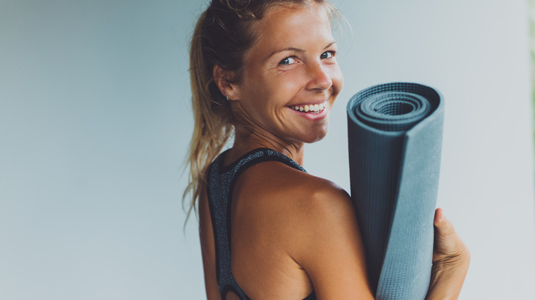 person carrying rolled yoga mat