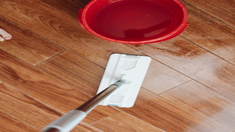 A red bucket with water on a bamboo floor