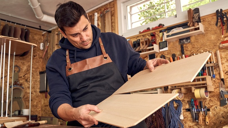 man in wood shop aligning two pieces of plywood at edges