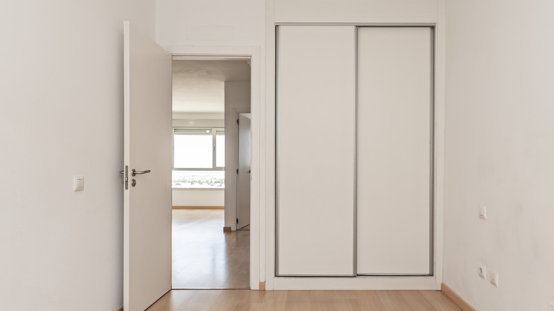 Bedroom with sliding closet doors in empty white apartment