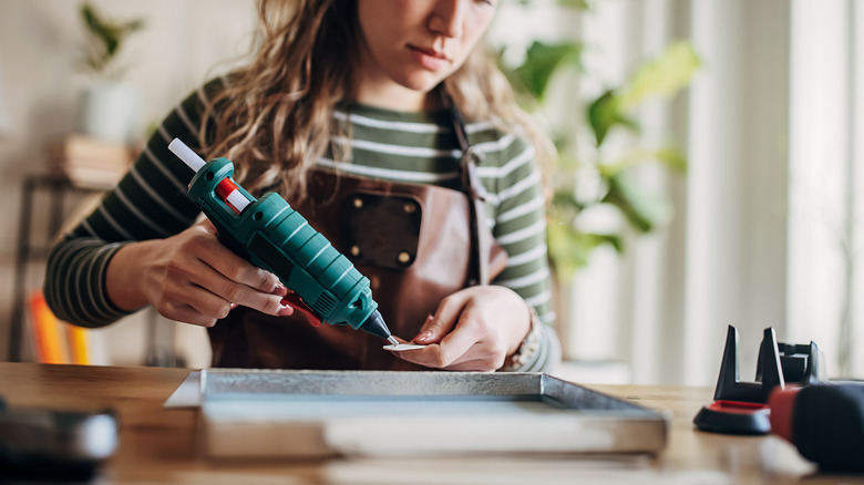 Woman gluing together items at desk to build a project