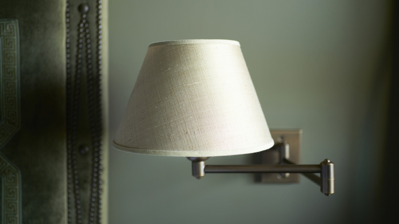 A basic beige lampshade is on a wall sconce