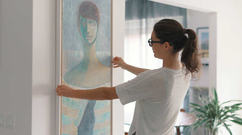 Woman hanging large painting