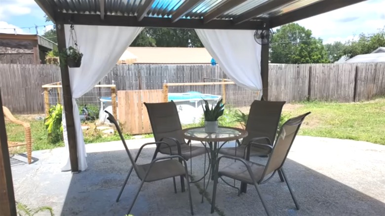 A DIY backyard awning is installed in a garden