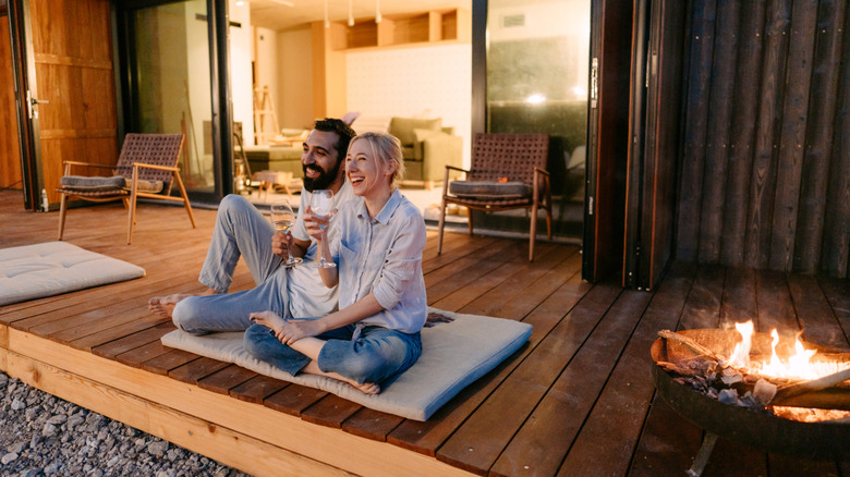 A couple sitting on a patio by a fire