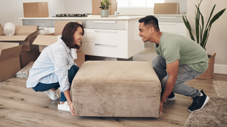 Two people moving an ottoman