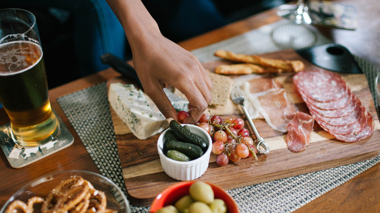 Hand picking out grapes from a charcuterie board