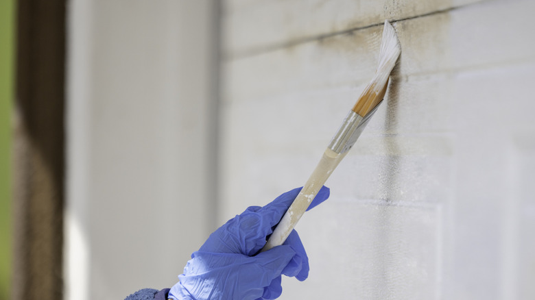 Person wearing gloves painting a white garage door