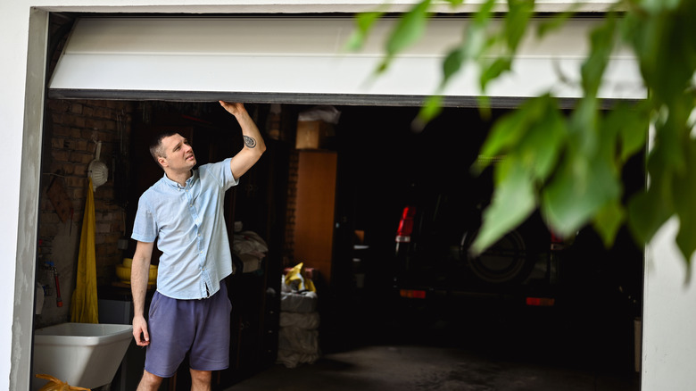 Man inspecting a white metal garage door