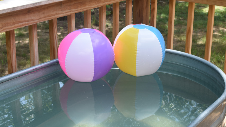 Two balls floating in an outdoor stock tank pool.