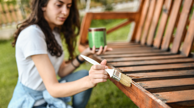 woman painting outdoor bench