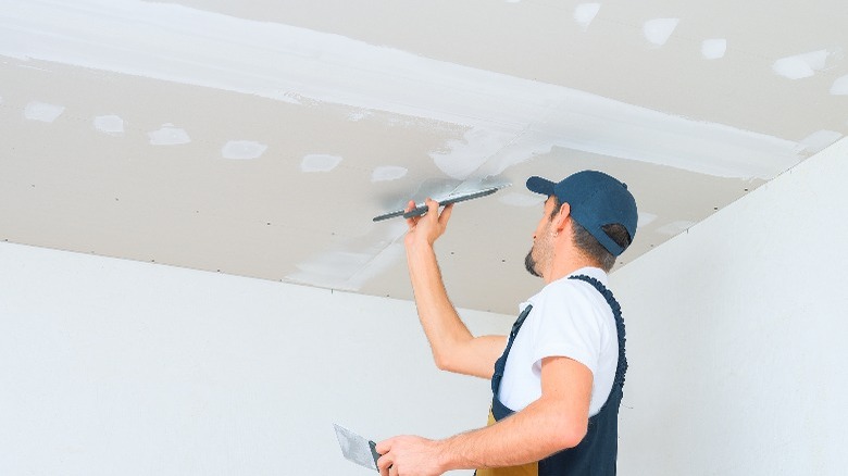 man mudding ceiling drywall